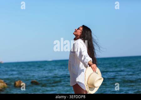 Frau, die auf Felsen steht und die Sonne genießt Stockfoto