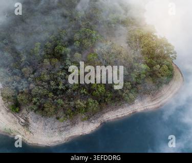 Blick aus der Vogelperspektive auf das Kangaroo Creek Reservoir mit dichtem Eukalyptuswald, umgeben von Morgennebel und ruhigem blauem Wasser Adelaide Hills Council, South Austra Stockfoto