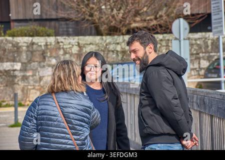 Eine Gruppe junger Menschen aus verschiedenen ethnischen Gruppen führt in Mänteln eine enge und angenehme Unterhaltung. Wintertage unter strahlendem Sonnenschein Stockfoto