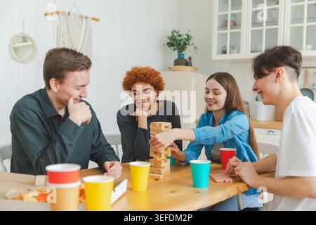 Heimmannschaft. Freunde, die zu Hause im Holzturm spielen. Glückliche, vielfältige Gruppe, die Spaß zusammen drinnen hat. Gemischte Rasse, junge Freunde, beste Freunde, die das Wochenende genießen Stockfoto