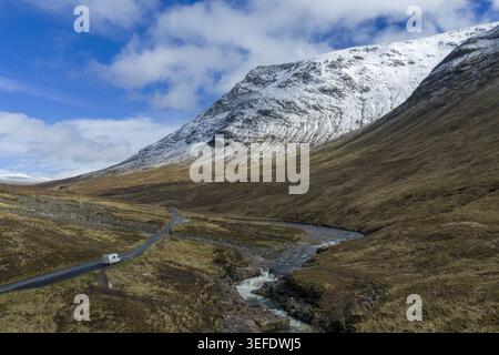 Blick aus der Vogelperspektive auf den Glen Etive Waterfall View Point mit einer gewundenen Straße, einem Wohnmobil und schneebedeckten Bergen in Ballachulish, Schottland, Großbritannien. Stockfoto