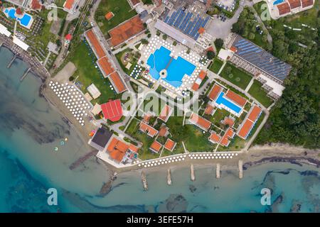 Blick von oben auf ein luxuriöses Sommerresort am Roda Beach in Korfu, Griechenland, mit großen Swimmingpools, orangen Dachgebäuden, Sandstrand mit Stockfoto