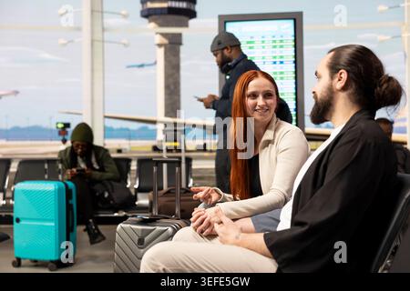 Hände im Flughafen halten, junges Paar kuschelt und redet, wartet auf den Flug. Urlaubsreisekonzept mit romantischen Partnern, die Sehenswürdigkeiten und Sehenswürdigkeiten während der Urlaubsreise planen. Stockfoto
