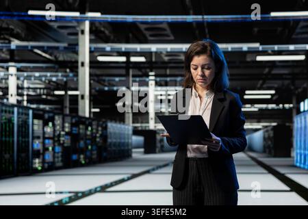 IT-Spezialist im Serverraum, der sich Diagnoseberichte zur Wartung ansieht, um die Leistung der Infrastruktur zu optimieren. Data Center-Techniker vergleichen technische Dateien, um unerwartete Systemausfälle zu verhindern Stockfoto