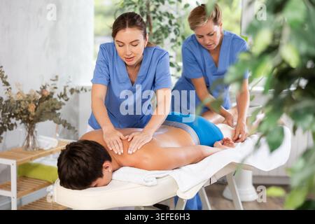 Entspannender junger Mann, der sich im Spa-Center massieren lässt Stockfoto