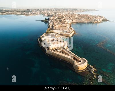 Aus der Vogelperspektive auf die Insel Ortigia mit Schloss Maniace umgeben vom blauen Mittelmeer in Syrakus, Sizilien, Italien. Stockfoto