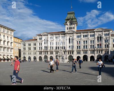 Großer Blick auf das Rathaus Palazzo del Municipio auf der Piazza Unita d'Italia mit Touristen, die auf dem Platz in Triest Italien spazieren gehen Stockfoto