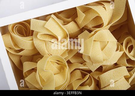 Rohe Pappardelle Nudeln, Nudelnester, in einem Papierkarton, Draufsicht, keine Leute Stockfoto
