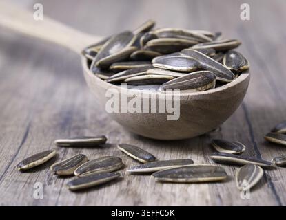 Gestreifte Sonnenblumenkerne in einem Löffel auf einem Holztisch. Nahansicht Stockfoto