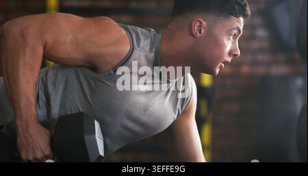 Fitness, Krafttraining oder Mann im Zentrum mit Hantel, Power oder abtrünniger Reihe im Bodybuilding. Sport, Schwitzen oder Person im Fitnessstudio mit Geräten Stockfoto