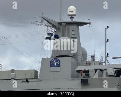 NATO-SYMBOLSCHILD AUF DEM GRAUEN MAST DES KRIEGSSCHIFFES HNLMS JOHAN DE WITT L801. DAS NATO-LOGO IST DEUTLICH SICHTBAR AM AUFBAU DIESES FLAGGENSCHIFFS. Stockfoto