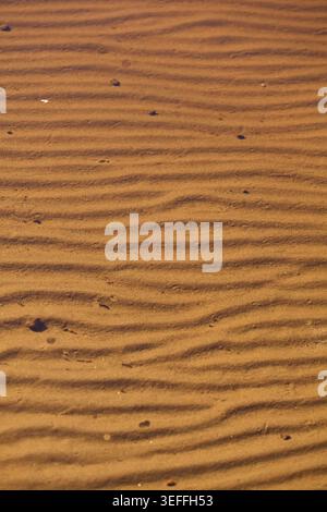 Sand in einem See, der durch die Bewegung des Wassers entstandene Wellen zeigt Stockfoto