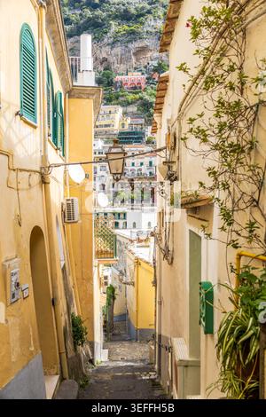 Charmante Gasse in Positano, Italien, mit pastellfarbenen Gebäuden, grünen Fensterläden und malerischem Blick auf die Hügel. Authentisches mediterranes Archit Stockfoto