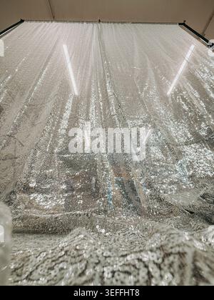 Funkelnde silberne Pailletten, die in einem Modestudio oder einem Stofflager hängen. Glamourös schimmernde Textur mit reflektierenden Details, ideal für Luxus Stockfoto
