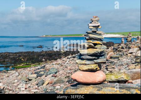 Cairn an einem felsigen Strand in der Nähe von John o' Groats, Nordschottland, an einem sonnigen Tag Stockfoto