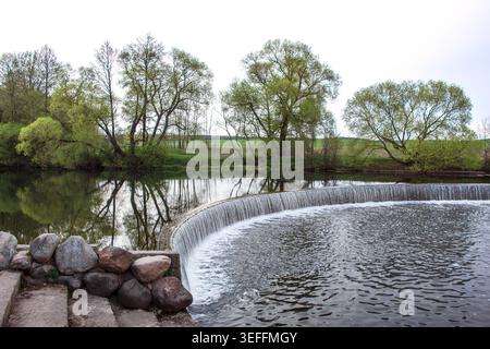 Ein künstlicher Wasserfall in einem Stadtpark. Eine Wasserkaskade mit Stufen im Stausee in der Nähe des Staudamms. Die Schönheit der Natur. Industrielle Architektur von Stockfoto