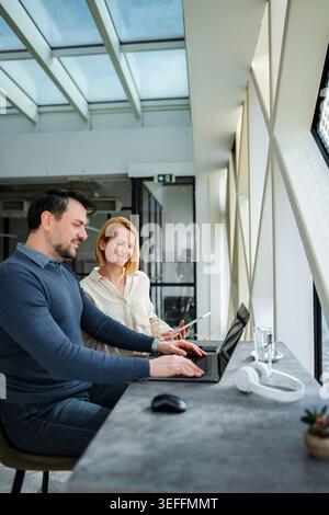 Profis, die im modernen Büro an einem Laptop und einem digitalen Tablet arbeiten Stockfoto
