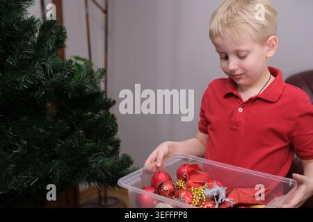 Kind mit weihnachtsschmuck, der immergrünen Baum schmückt Stockfoto