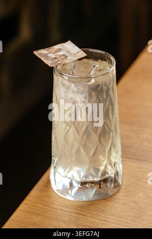 Eisiger Highball-Cocktail in einem gemusterten Glas auf Holz Stockfoto