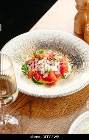 Eleganter Tomaten- und Stracciatella-Salat mit Weißwein Stockfoto