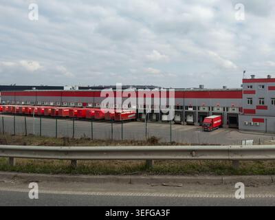 Chmelnytskyi, Ukraine - 30. März 2026: Das Lagerhaus Nova Poschta verfügt über mehrere Ladebuchten und geparkte rote Transportwagen für eine effiziente Nutzung Stockfoto