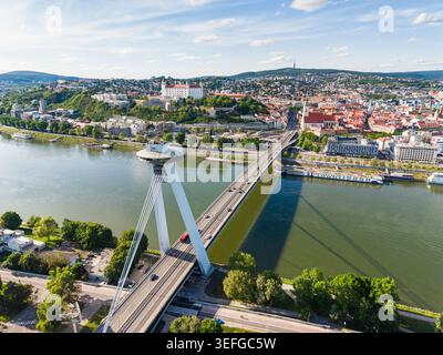 Aus der Vogelperspektive auf die SNP-Brücke mit ihrer UFO-Aussichtsplattform, die die Donau überquert, in Richtung Burg Bratislava auf dem Hügel in Bratislava, Bratislava Stockfoto