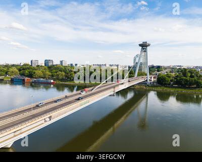Blick aus der Vogelperspektive auf die meisten SNP-Brücke mit ihrer berühmten UFO-Aussichtsplattform über die Donau, umgeben von üppigen grünen Bäumen und Stadtgebäuden, Bratisla Stockfoto