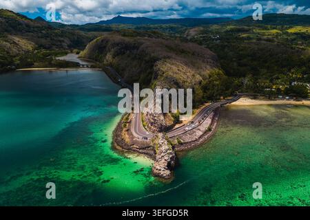 Blick aus der Vogelperspektive auf den Maconde Aussichtspunkt und die gewundene Küstenstraße entlang der türkisfarbenen Lagune und der üppigen grünen Berge im Moka District, Mauritius. Stockfoto