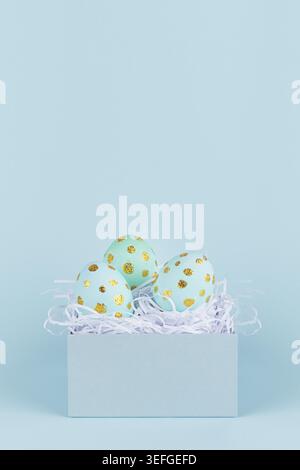 Einfachheit und minimales Design von ostereiern mit Gold in Geschenkbox auf blauem Hintergrund, vertikal. Stockfoto