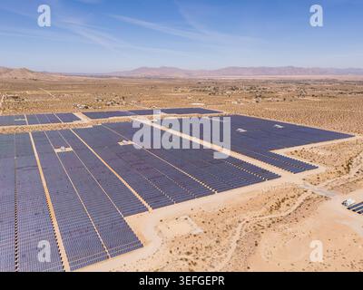 Luftaufnahme eines riesigen Solarparks mit Reihen von blauen Panels, die sich über die trockene Wüstenlandschaft unter klarem Himmel erstrecken Lucerne Valley, Kalifornien, UN Stockfoto