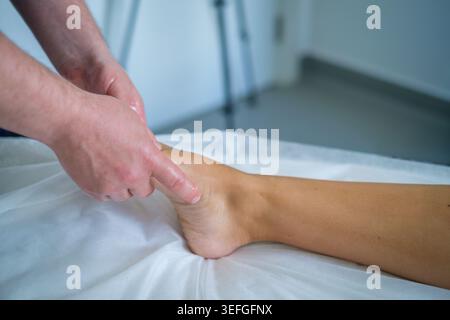 Ein erfahrener Therapeut bietet eine wohltuende Fuß- und Beinmassage mit Öl zur Entspannung und Lymphdrainage in einer beruhigenden Spa-Umgebung. Stockfoto