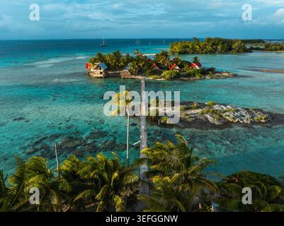 Blick aus der Vogelperspektive auf ein tropisches Motu mit Bungalows mit rotem Dach und einer langen Holzbrücke über türkisfarbenem Wasser in Moorea-Maiao, Windward Islands, French Poly Stockfoto