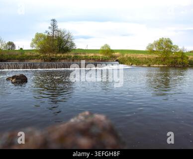Ein künstlicher Wasserfall in einem Stadtpark. Eine Wasserkaskade mit Stufen im Stausee in der Nähe des Staudamms. Die Schönheit der Natur. Industrielle Architektur von Stockfoto