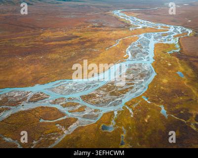 Aus der Vogelperspektive eines geflochtenen Flusses, der sich durch die lebhafte herbstliche Tundra-Landschaft in der Nähe des Dalton Highway in Coldfoot, Alaska, USA schlängelt. Stockfoto