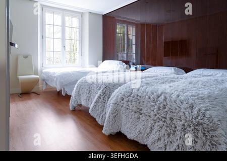 Budget-Hotelzimmer mit drei Betten in kompakter, gemeinschaftlicher Anordnung. Stockfoto