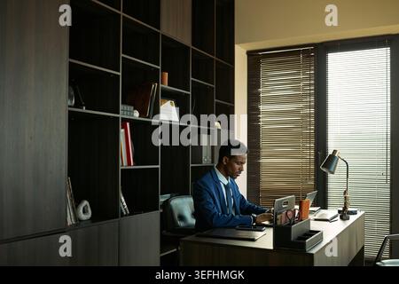 Große Aufnahme eines afroamerikanischen jungen erwachsenen Geschäftsmannes, der am Schreibtisch in der Anwaltskanzlei arbeitet und Dokumente des Scheidungsfalls überprüft. Geeignet für Rechtsdienstleistungen, Familienrecht, Mediationsmarketing Stockfoto