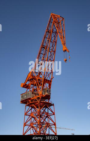 Blick auf den historischen roten Carola-Kran, der hoch vor einem klaren blauen Himmel an den Anlegestellen des maritimen Museums im Großraum Bilbao, Baskenland, Spanien steht. Stockfoto