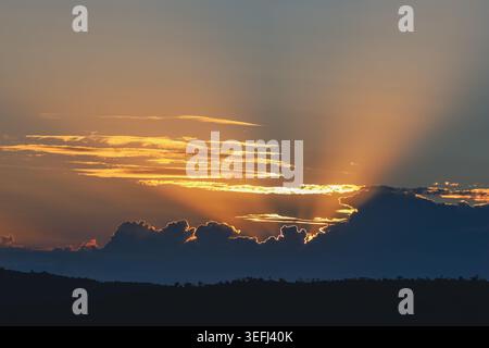 Blick auf goldene Sonnenstrahlen, die durch dunkle Wolken über dem Horizont des Welgevonden Game Reserve in der Gemeinde Waterberg brechen, Stockfoto