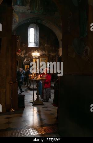 Gläubige zünden Kerzen vor Ikonen in der kunstvoll verzierten Georgisch-orthodoxen Kirche mit alten Fresken, Tiflis, Georgien - 27. April 2026. Stockfoto