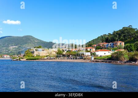 Das Küstendorf Petra auf der Insel Lesbos bietet traditionelle Häuser entlang der Küste mit üppigen grünen Bergen und einem ruhigen blauen Ägäis unter einem Stockfoto