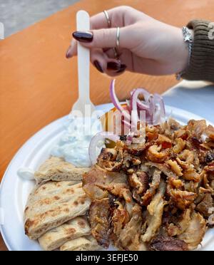 Authentische griechische Essensplatte mit Gyros-Fleisch, Pitabrot, Tzatziki-Sauce, Tomaten und roten Zwiebeln auf einem Holztisch. Draufsicht. Stockfoto