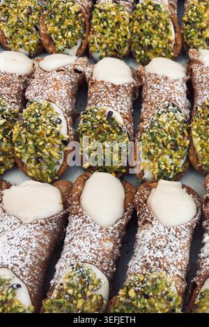 Tablett mit authentischem italienischem Cannoli-Gebäck gefüllt mit süßer Ricotta-Creme, Puderzucker und gehackten Pistazien. Stockfoto