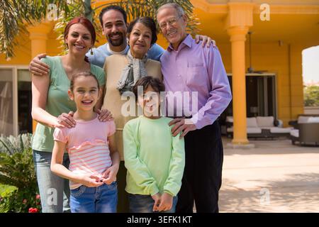 Eine mehrgenerationenübergreifende arabische Familie aus dem Nahen Osten lächelt zu Hause im Freien zusammen für ein glückliches Familienporträt Stockfoto