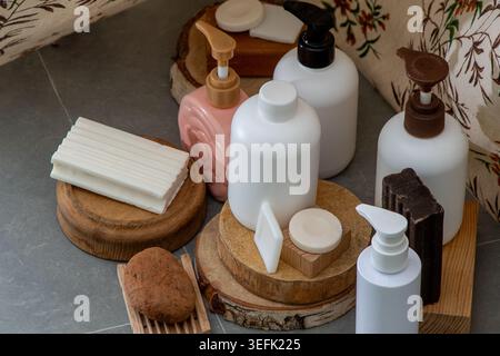 Flaschen mit Seife und weißer Lotion. Natural Skincare Collection mit Seifenstangen und Kosmetikflasche auf Holzpodesten von oben Stockfoto