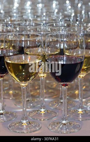 Reihen von Weingläsern gefüllt mit Rot- und Weißwein auf einem Tisch für eine Feier. Stockfoto