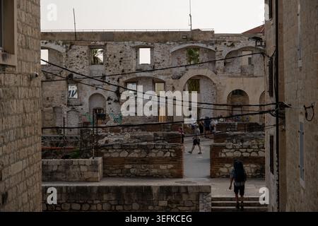 Split, Kroatien - 1. September 24: Blick durch eine enge Straße zu alten Steinruinen mit bogenförmigen Öffnungen und Besuchern im Diokletianpalast, Split Stockfoto