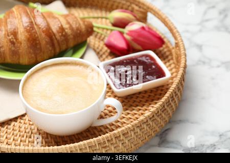 Tablett mit leckerem Frühstück und Tulpenblüten auf weißem Marmortisch Stockfoto