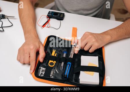 Draufsicht des Lötkolbensatzes mit kleiner Schaltung, Vorbereitung einer präzisen elektronischen Reparatur oder Montage mit offenem Werkzeugsatz von Komponenten und Stockfoto