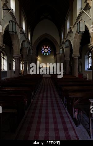 Das Innere der Kirche unserer Lieben Frau und des Heiligen Finnan in Glenfinnan zeigt das Kirchenschiff, Holzbänke, gotische Bögen und Buntglasrosen über dem al Stockfoto