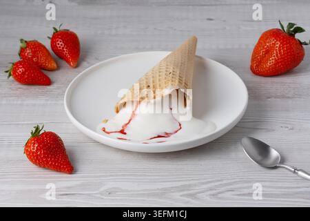 Erdbeereis in Waffelform und Erdbeeren auf einem weißen Holztisch Stockfoto
